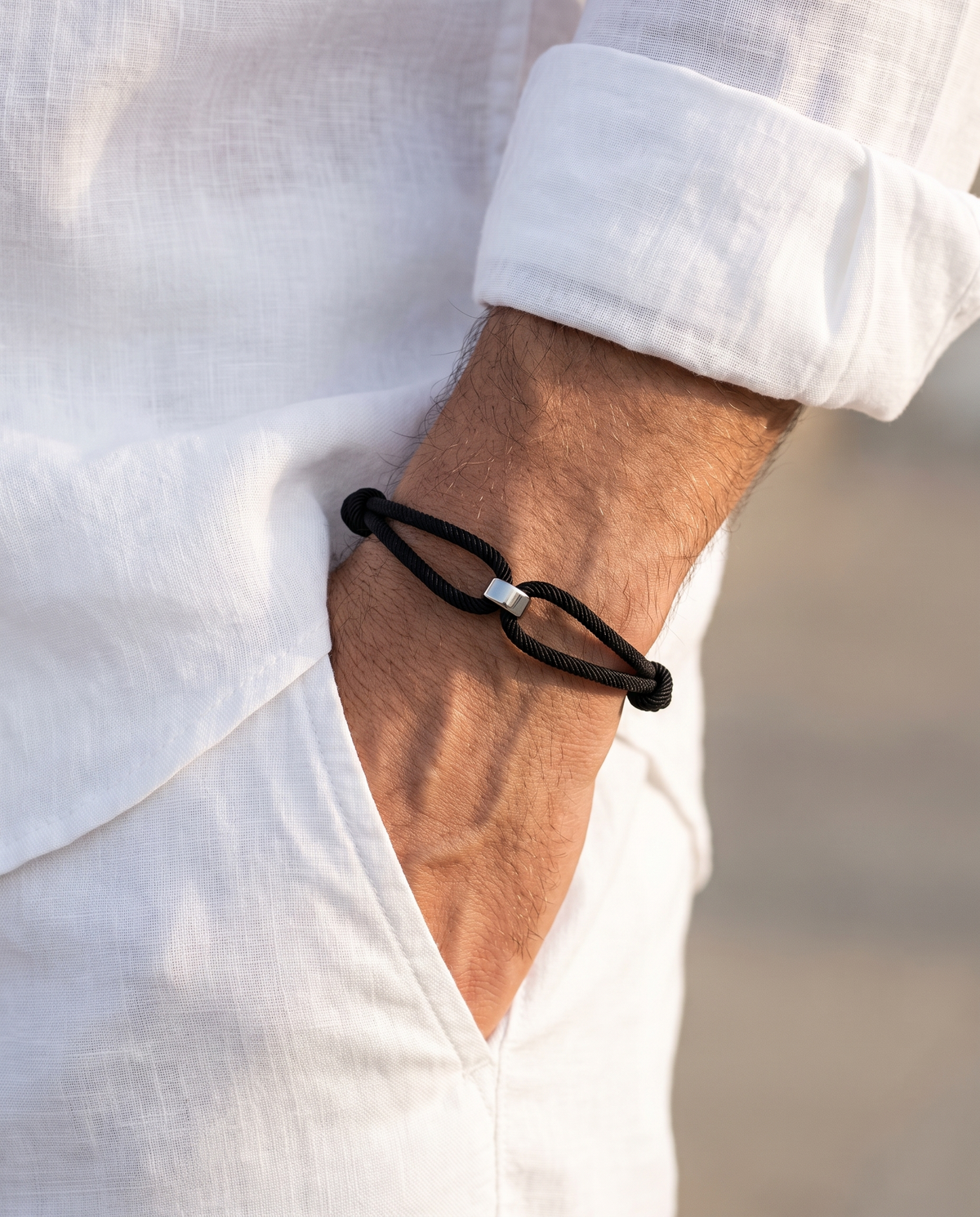 Man in a white linen shirt wearing the Milan Cord bracelet, hand in his white linen trouser pocket