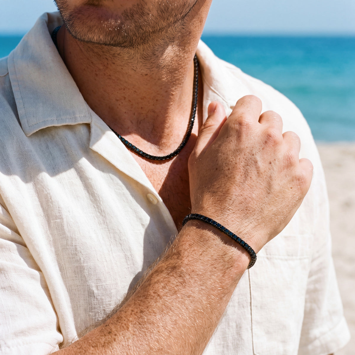 Man wearing the Noir tennis chain and bracelet together on the beach