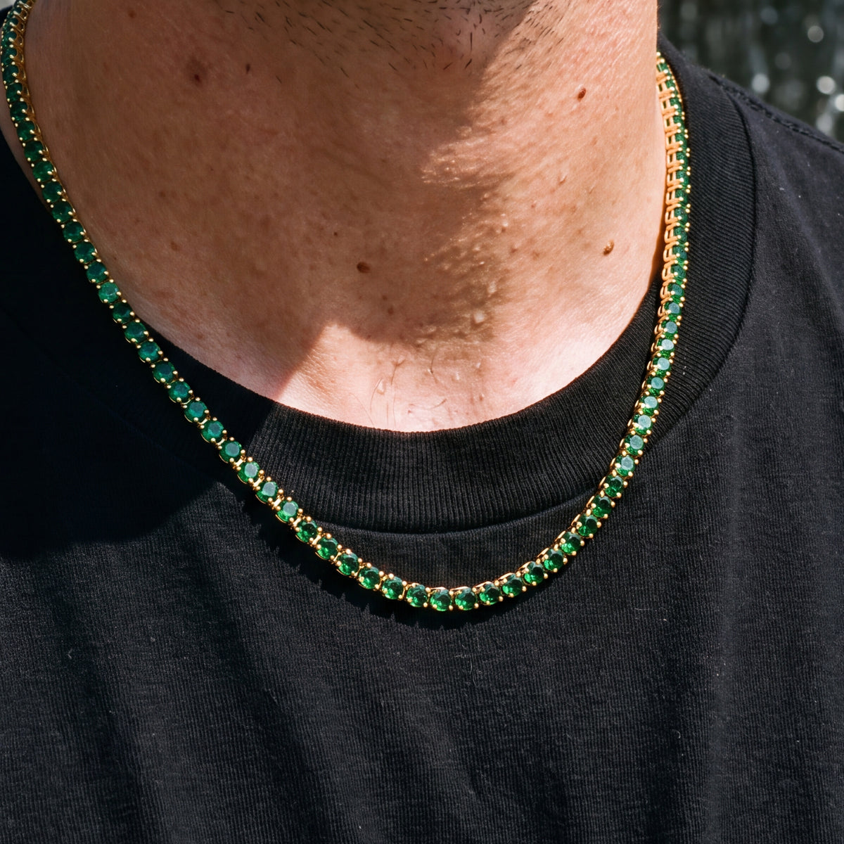 Close-up of the Green Day Dore Chain's green stones in gold settings on the neck