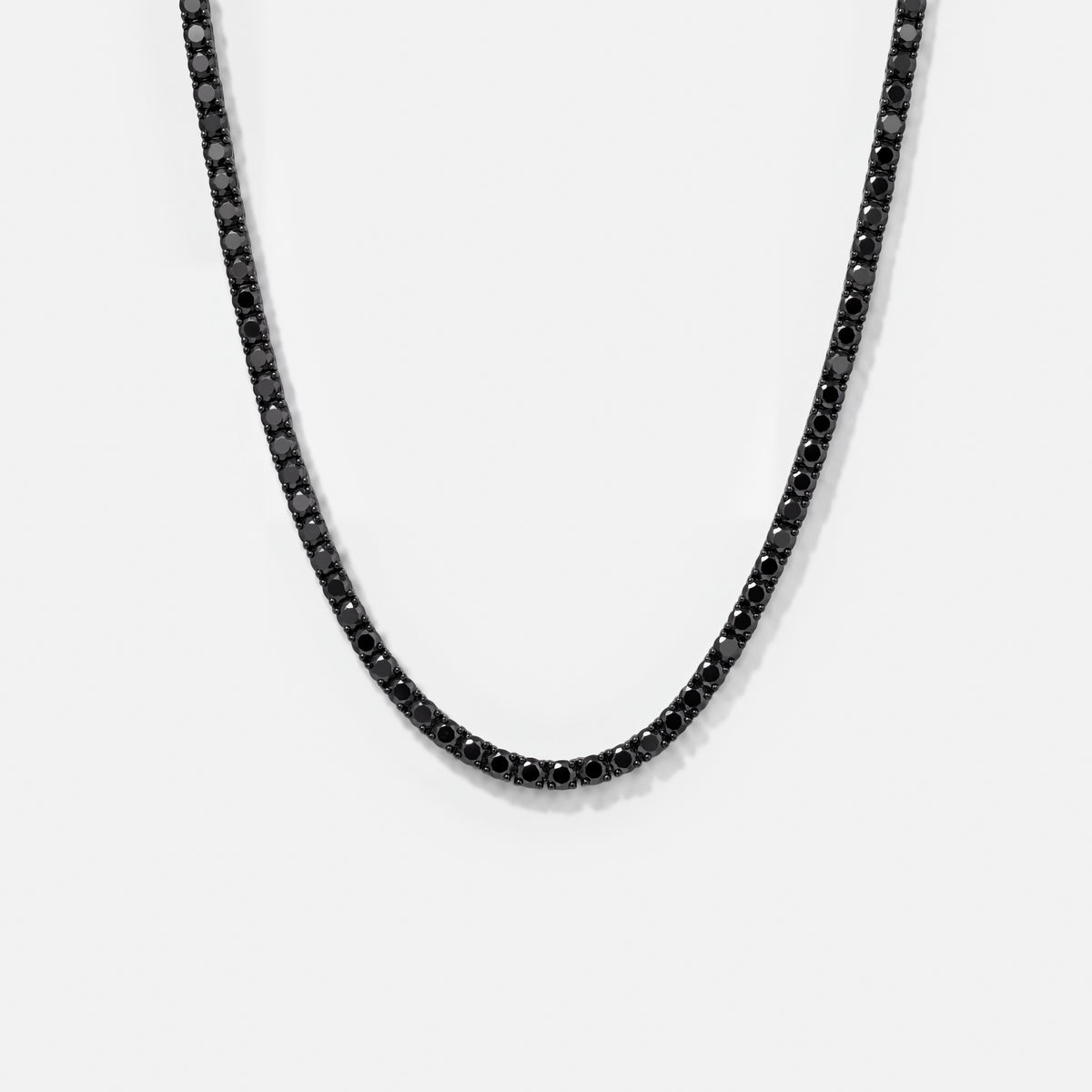 Noir Chain all-black tennis necklace on a light grey background