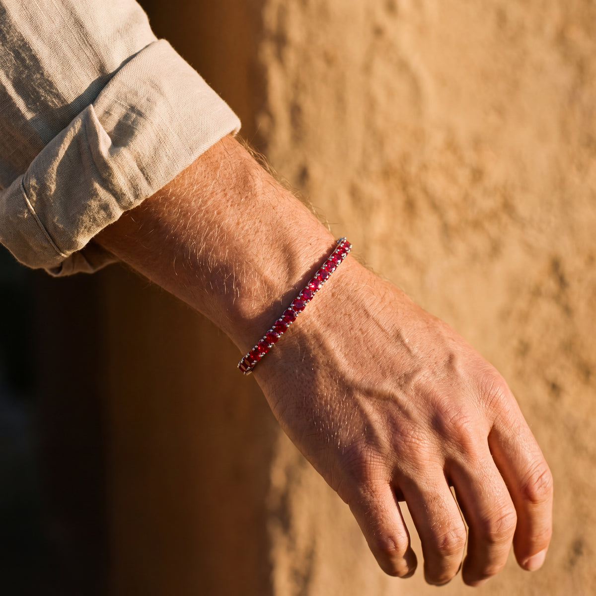 Rubi Garnet bracelet worn on the wrist against a sunlit ochre wall
